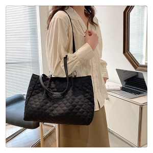 Close-up of quilted nylon tote bag with Fashion label in a minimalist office setting