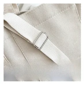 Détail de la boucle métallique argentée sur la bandoulière en toile beige d'un sac