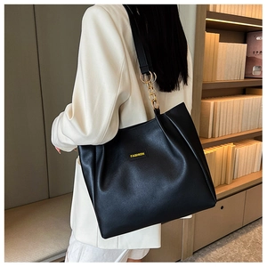 Detail of black matte PU leather tote bag with gold chain strap and fashion label on front