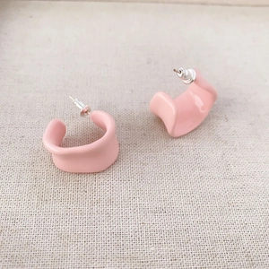Pink irregular C-shaped enamel earrings with 925 silver needle on beige fabric background