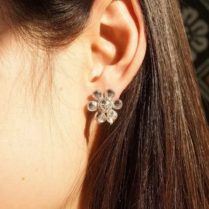 Boucles d'oreilles fleurs élégantes avec pétales transparents portées par un modèle