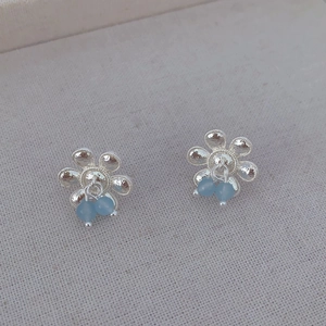 Détails de boucles d'oreilles fleurs en argent avec pétales ciselés et perles bleu clair