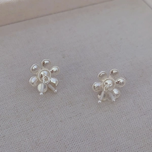 Boucles d'oreilles fleurs en argent avec perles mates sur fond de lin beige