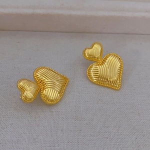 Textured gold double heart earrings with elegant vertical ribbing on a neutral fabric