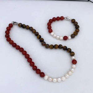 Detail of red agate, tiger eye, and baroque pearl beaded jewelry set with silver clasps