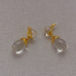 Elegant gold-plated drop earrings featuring clear teardrop crystals on light fabric