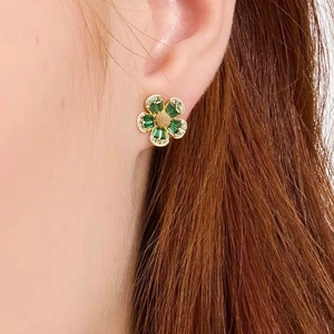 Elegant floral stud earrings with green rectangular stones and gold-tone center on ear
