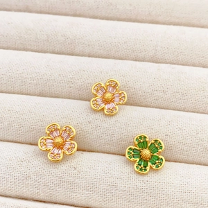 Elegant gold flower earrings with pink and green zircon stones on velvet display