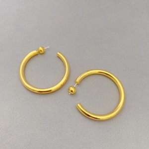 Detailed view of large gold hollow C-shaped hoop earrings with a smooth polished finish