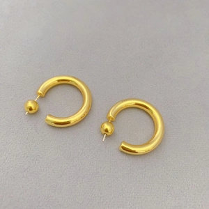 Detailed view of hollow chunky C-shaped gold hoop earrings with metallic bead accents