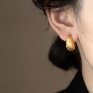 Matte goldene Creolen mit Sternengravur und kleinem Zirkonia-Inlay am Modell