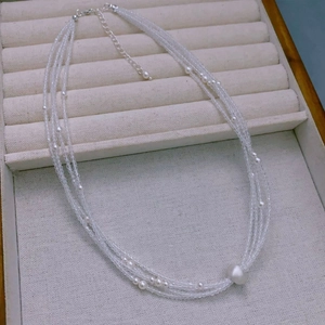 Detail of multi-layer beaded necklace with clear crystals and baroque pearl pendant