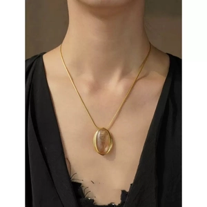 Detalle de collar vintage con colgante ovalado de cristal de té usado por una modelo