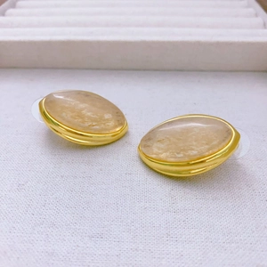 Vista detallada de pendientes ovalados vintage con marco dorado y textura mármol
