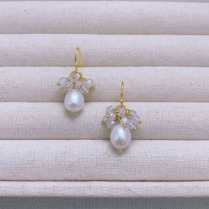 Detailed close-up of water drop pearl earrings with faceted crystals on gold hooks