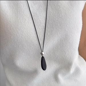 Fashionable teardrop black agate pendant necklace worn by a model on a white knit sweater