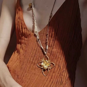 Artistic gold flower pendant necklace with woven cord displayed on a model