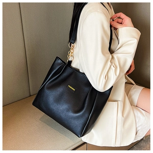 Detail of black pebbled leather tote bag with yellow Fashion label and gold chain strap