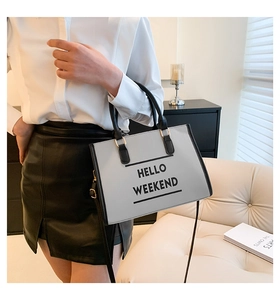 Détail du sac cabas gris-blanc avec texte HELLO WEEKEND et boucles métalliques dorées