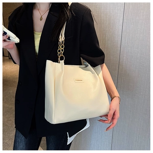 Detail of off-white tote bag with gold chain strap and Fashion lettering on metal plate