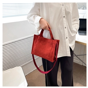 Détail du sac cabas en velours côtelé rouge avec bandoulière porté par un mannequin