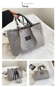 Detail view of grey quilted nylon tote bag with chain handles and fashion logo