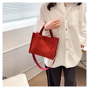 Détail du sac bandoulière en velours côtelé rouge avec poche avant et sangle réglable