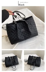 Macro view of black quilted nylon tote bag with fashion instinct label and chain strap