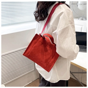 Sac cabas en velours côtelé rouge avec bandoulière et poignée porté par un mannequin