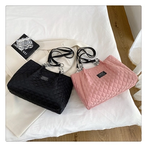 Detail of quilted nylon tote bag with silver chain strap and fashion label on front