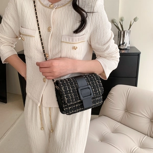 Sac bandoulière élégant en tweed noir et doré avec chaîne porté par une femme chic