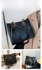 Detail of black leather tote bag with fashion letter logo and gold chain strap accents