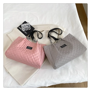 Detail of pink and grey quilted tote bags with fashion label and chain straps