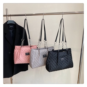 Detailed view of quilted tote bags in pink grey and black with chain straps