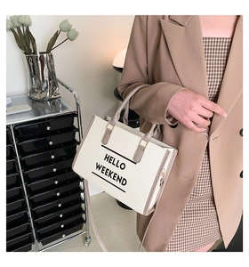 Détail du sac fourre-tout crème avec imprimé Hello Weekend et poignée contrastée marron