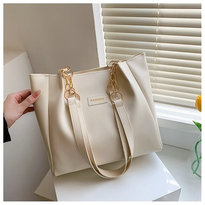 Close-up of beige faux leather tote bag with metal chain strap and fashion label detail
