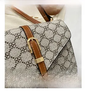 Detail of clover patterned fabric texture with brown leather strap and gold buckle