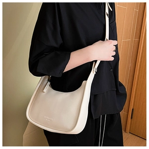 Close-up of cream hobo bag with gold fashion bag lettering and textured finish