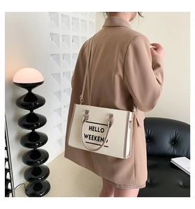 Détail du cabas minimaliste avec imprimé 'HELLO WEEKEND' et poignées en cuir marron