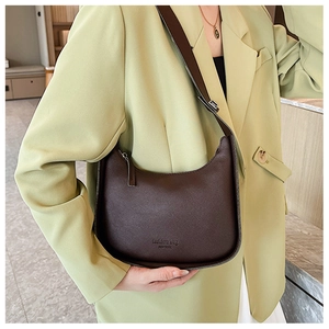 Brown faux leather crescent bag styled on shoulder over light green blazer outfit