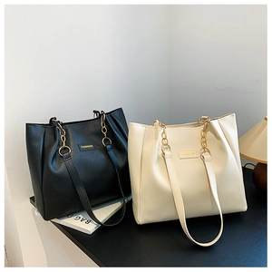 Close-up of black and cream large tote bags with gold chain straps and fashion labels