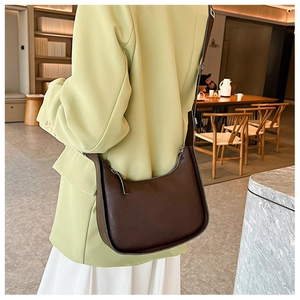 Detail of dark brown semi-circle bucket bag with debossed text on smooth matte leather