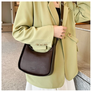 Detail of dark brown matte leather half-moon bag worn by model in casual style