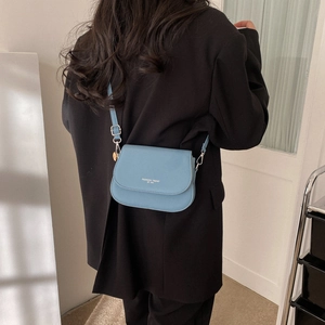 Sacoche selle minimaliste bleu clair en cuir avec bandoulière réglable sur blazer noir