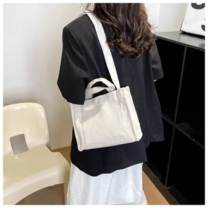 Détail de la vue arrière d'un sac cabas en toile blanche porté à l'épaule pour femme