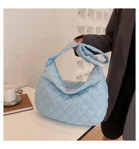 Close-up of light blue quilted tote bag showing diamond stitching and puffy shoulder strap