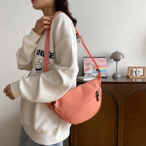Sac bandoulière demi-lune en nylon rose corail avec large sangle porté par un mannequin