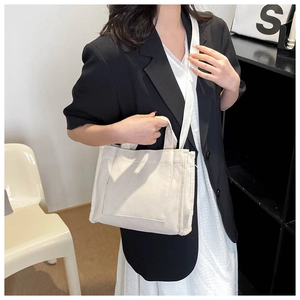 Détail du sac cabas en toile blanc cassé avec bandoulière et poche frontale