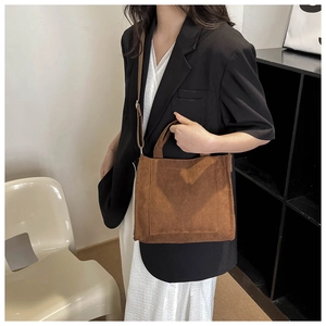 Détail d'un sac cabas en velours côtelé marron foncé avec bandoulière sur un mannequin