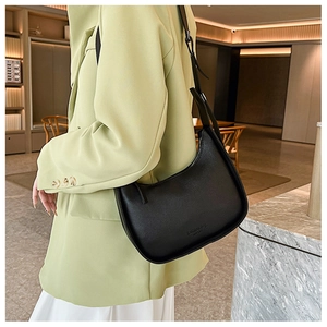 Detail of a chic black crescent hobo bag worn with a stylish light green blazer